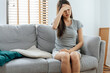 © Vittaya_25 - asian young woman touching forehead having headache migraine and upset with problem feel stressed sitting on couch in living room at home, people painful, depression, medical and health care concept