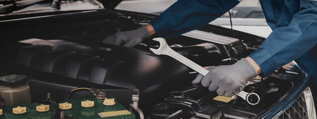 The mechanic works on the engine of the car in the garage, car repair service.