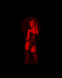 Sexy blonde dominatrix woman behind door keyhole in red light