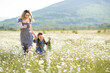 © morrowlight - Cute beautiful young woman walking holding hand of little child girl walk in chamomile field with blooming flowers over nature background. Family lifestyle concept. Mom and baby daughter together.