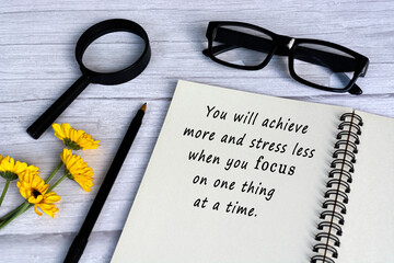 Wall Mural - Motivational quote on note book with magnifying glass on white wooden desk.