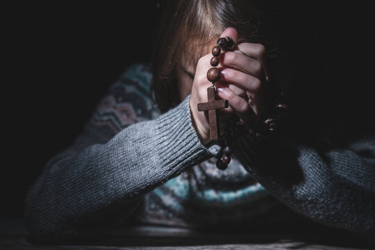 Prayer to God. Portrait of young girl pray with rosary. Faith concept. Copy space for text.
