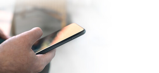 Wall Mural - Close-up, a man uses a smartphone while browsing the Internet, searching for data on the network, or browsing social networks.