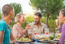Happy Friends Laughing With Big Smile Around The Table In A Summer Diner. Smiling People Eating At House Patio. Smiles, Cheerfulness Concept.