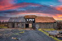 Traditional Wooden House Surrounded By Fence. Historic Viking Village Near Stokksnes In Volcanic Valley. Scenic View Of Ancient Attraction Against Dramatic Sky During Sunset.