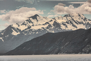 Wall Mural - Skagway, Alaska, USA - July 20, 2011: Taiya Inlet above Chilkoot Inlet. Wide landscape with snow covered mountain along gray-gray ocean water under blue cloudscape.