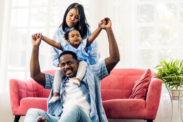 Wall Mural - Portrait of enjoy happy love black family african american father and mother with little african girl child smiling and play having fun moments good time in room at home