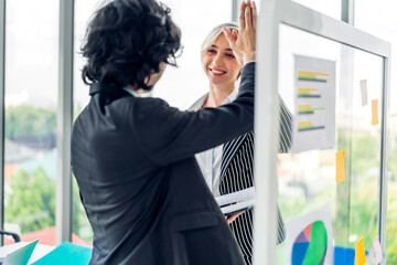 Casual creative happy two smile usiness people plan strategy analysis and brainstorm putting post it sticker note to share idea for startup project on glass board at modern office