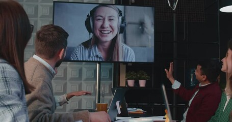 Wall Mural - Team of business people wave, talk to female CEO, manager via web conference, video call at office meeting slow motion.