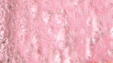 Slow Motion Close-up Pouring Water In Glass On Pink Rose Background With Bubbles