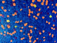 A Blue, Roughly Pixelated Surface With Orange And Yellow Speckled Dots