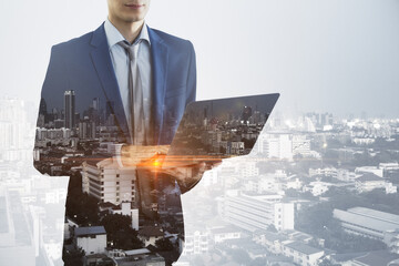 Wall Mural - Headless young european businessman with laptop standing on abstract bright city background with mock up place. Success, technology, communication and employment concept. Double exposure.