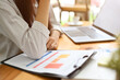 © bongkarn - Cropped, close-up image, Businesswoman working at her office desk, reading a financial report.