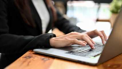 Close-up image, Female office worker working on laptop computer, typing on keyboard