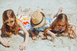 three happy children lie on the sand on the beach.a child with down syndrome with friends has fun on the beach.