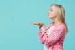 © ViDi Studio - Side profile view young happy caucasian woman she 30s wears pink shirt white t-shirt blowing sending air kiss isolated on plain pastel light blue background studio portrait. People lifestyle concept.