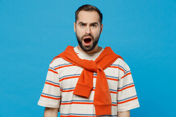 Young indignant displeased dissatisfied angry sad caucasian man 20s wear orange striped t-shirt looking camera scram shout isolated on plain blue background studio portrait. People lifestyle concept.