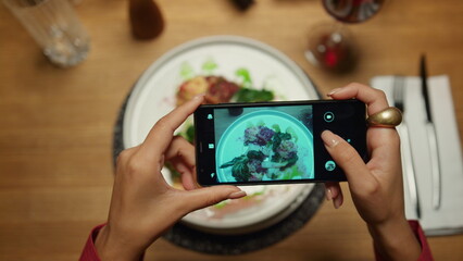 Wall Mural - Woman taking photos dinner using mobile phone in restaurant. Lady enjoying meal.