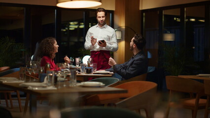 Wall Mural - Restaurant waiter taking order serving romantic couple on evening dinner date.