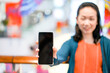 © Surachetsh - Black screen of mobile in Asian woman hand with blur face in department store background. For mock up website or application on smart phone. Clipping Path.