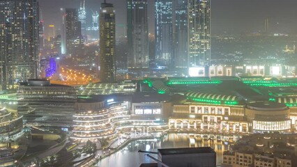 Wall Mural - Dubai downtown with fountains and modern futuristic architecture aerial during all night timelapse. View to skyscrapers under construction with shopping mall. Lights turning off