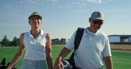 Wall Mural - Rich couple talking golf sport outside. Two country club members walk on fairway