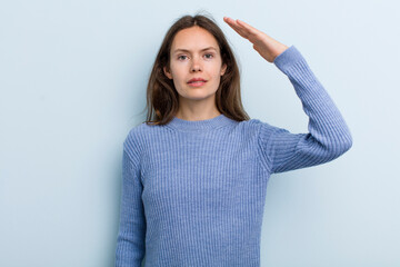 Wall Mural - young adult pretty woman greeting the camera with a military salute in an act of honor and patriotism, showing respect