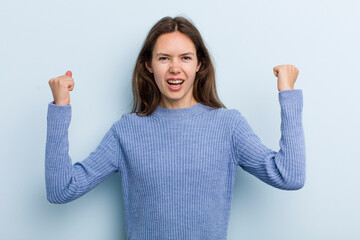 Wall Mural - young adult pretty woman shouting aggressively with an angry expression or with fists clenched celebrating success