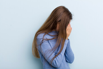 Wall Mural - young adult pretty woman covering eyes with hands with a sad, frustrated look of despair, crying, side view