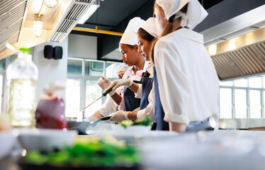 Senior asian woman chef teach student. Cooking class. culinary classroom. group of happy young woman multi-ethnic students are focusing on cooking lessons in a cooking school.