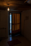 Fototapeta Psy - Creepy door half open in an old house with light bulb hanging from wooden ceiling