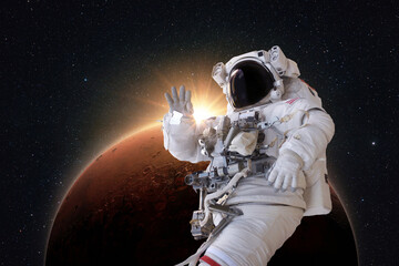 Wall Mural - successful astronaut in a space suit levitates in space and explores the amazing red planet mars wit