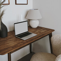 Wall Mural - Laptop computer with blank screen on table with lamp and flowers bouquet. Aesthetic influencer boho styled home workspace interior design template with mockup copy space. Online store, blog branding