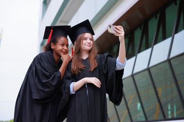 Wall Mural - student wearing gown and making photo by smartphone  graduating. Happy graduate success and celebration. Congratulation