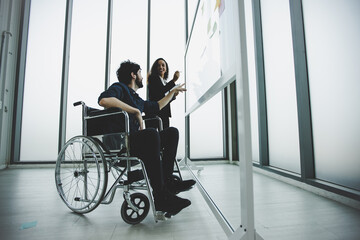 young disabled businessman wearing in wheelchair working and discus with colleague, planning and brainstorming concept