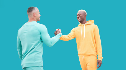 Multi ethnic friends. Two men different color black African-American ethnicity and white Caucasian ethnicity standing isolated blue background