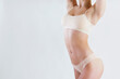 © Evrymmnt - Cropped shot of unrecognizable fit woman in lingerie isolated on white background. Torso of slim attractive female with flat belly in white underwear. Copy space for text, close up.