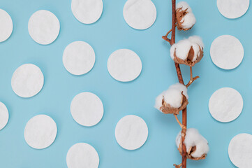 Wall Mural - White cotton hygienic pads, sanitary swabs, branch of cotton flowers on blue background, flat lay top view. Concept of hygiene, personal care, makeup remover cosmetic discs. Spa, beauty, skin care