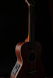 © Kullaya - Ukulele brown wood grain in dark light for playing on black background.