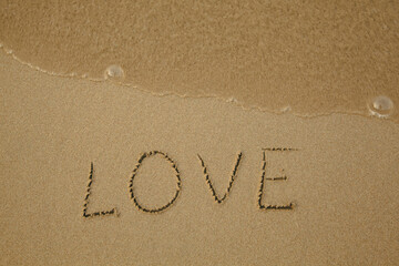 Wall Mural - Love - drawing on the soft beach sand with a soft lapping wave.