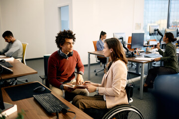 Wall Mural - Black computer programmer and his colleague with disability cooperating while working at corporate office.