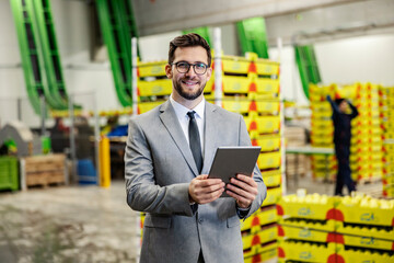 Portrait of a business owner using tablet in storage and smiling at the camera.