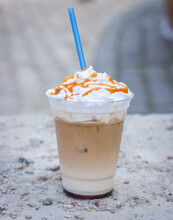 Cold Latte With Whipped Cream And Drinking Straw. Iced Latte Decorated With Salt Caramel Topping. Cold Drinks. Frappe Coffee With Straw. Frozen Cappuccino With Syrup. Coffee To Go. Summer Drinks.