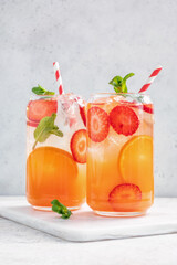 Wall Mural - Delicious Orange lemonade with strawberries on grey table, space for text. Fresh summer cocktail