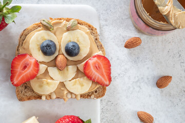 Wall Mural - Kids breakfast or lunch or snack toast with peanut butter spread, banana, strawberry and blueberry shaped as cute owl.