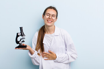 Wall Mural - young adult woman laughing out loud at some hilarious joke. scientist with a microscope