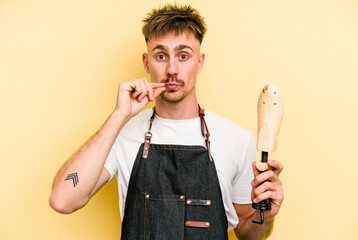 Wall Mural - Young shoemarket man isolated on yellow background with fingers on lips keeping a secret.