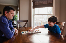 Boy And His Father Having Fun Playing A Game Together At Home.
