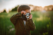 © Cavan Images - Hipster little boy with vintage camera outdoors. Child in costume