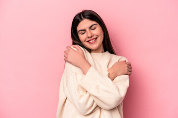 Wall Mural - Young caucasian woman isolated on pink background hugs, smiling carefree and happy.